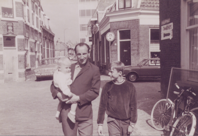 862749 Portret van vader Jupijn met z'n zoons Marco (2 jaar, op de arm) en Alex (9 jaar), op de hoek van de ...